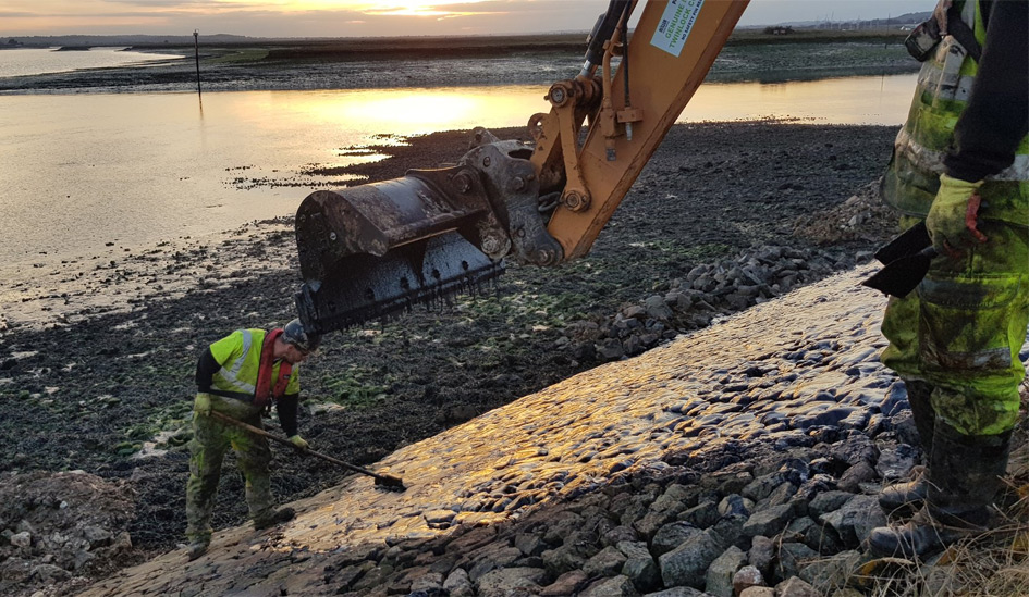 Man working next to digger at the shoreline